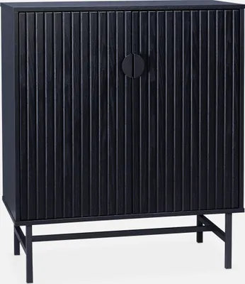 A black cabinet with fluted doors and a circular handle, shown on a white background with thin black legs.