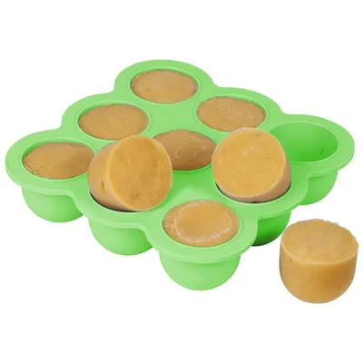 A green silicone mold filled with tan-colored baby food portions, with one portion removed and placed next to the mold.