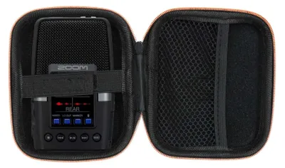 A black protective case is open, showing a black digital audio recorder inside. The case has an orange trim.