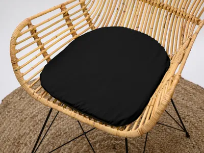 A black cushion on a rattan chair.