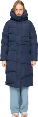 A woman wearing a dark blue puffer coat and light blue pants, standing against a white background.
