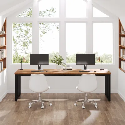 A modern home office setup with a large wooden desk and two computers, positioned in front of a large window.
