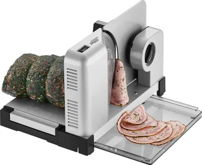 A meat slicer is shown with a large piece of meat on the left, and several slices of processed meat on a tray on the right.