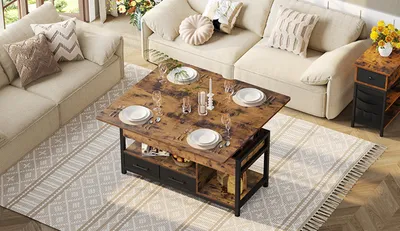 A living room scene with a coffee table set for a meal, placed on a rug in front of a sofa.