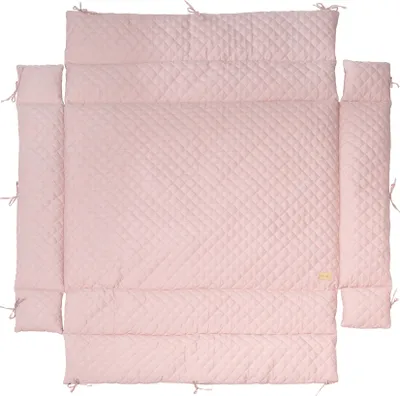 A quilted pink crib bumper pad laid out flat on a white background.