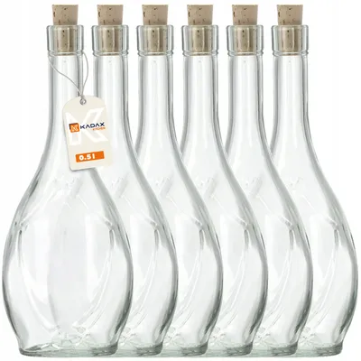 A group of six clear glass bottles with cork stoppers, arranged in a row against a white background. One bottle has a tag attached.