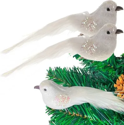 Three white decorative birds with glitter accents are perched on a green artificial Christmas tree branch.
