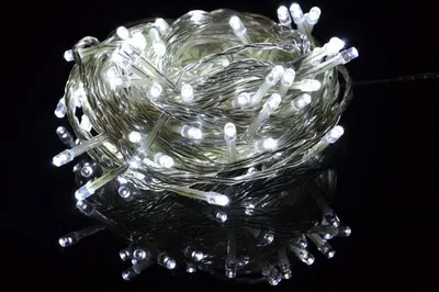A coiled string of white LED lights on a reflective black surface.