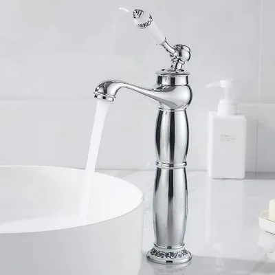 A chrome-finished faucet with a white ceramic handle is shown in a bathroom setting, with water flowing into a white sink.