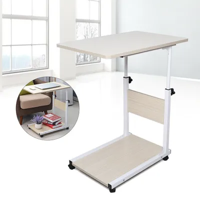 A mobile laptop table with a light wood finish and white metal frame, shown in a room with large windows.
