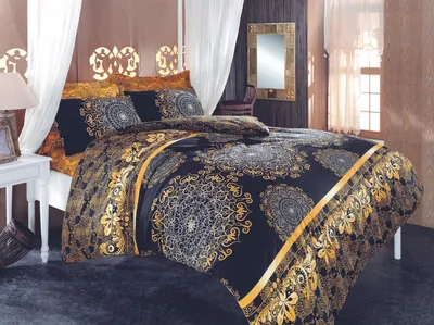 A bedroom scene with a bed dressed in ornate black and gold bedding.