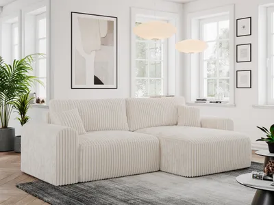 A modern living room with a beige cord sofa, plants, and artwork.