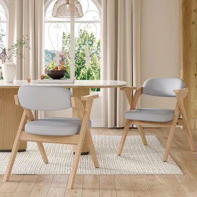 Two dining chairs are placed around a dining table in a well-lit room with large windows.