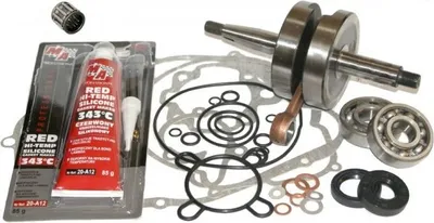 A collection of motorcycle engine parts, including a crankshaft, bearings, seals, and gasket material, laid out on a white background.