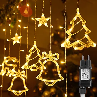 Christmas lights in the shape of stars, trees, bells, and a reindeer, hanging against a dark, blurred background, with a power adapter visible on the right.