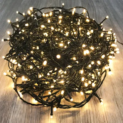 A tangled pile of warm white LED string lights on a wooden floor.