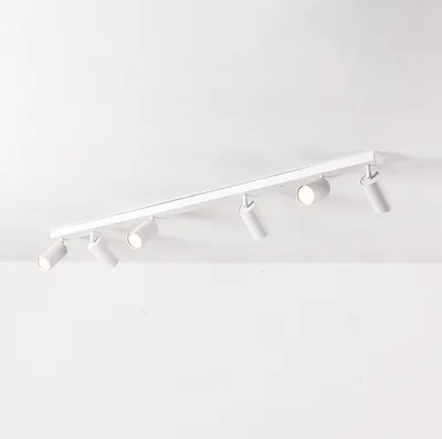 A white track light fixture with six adjustable spotlights mounted on a white ceiling.