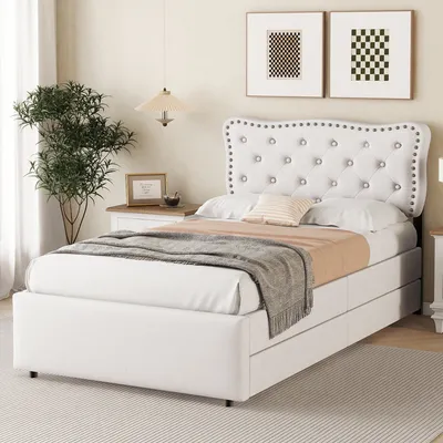 A bedroom scene featuring a white upholstered bed with a tufted headboard and storage drawers.