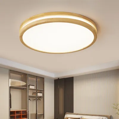 A modern ceiling light fixture with a wooden frame and a white diffuser, installed on a white ceiling in a bedroom with a closet and a bed visible.