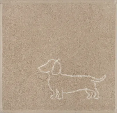 A close-up of a beige towel with a white outline of a dachshund dog.