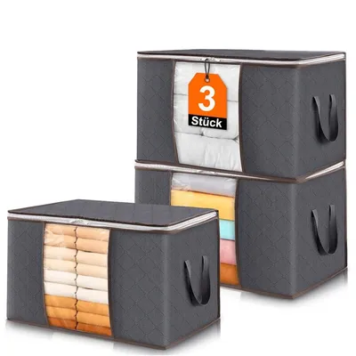 Three stacked storage boxes, with one box in the foreground and two stacked behind it. The boxes are dark gray with quilted patterns and handles. The front of the foreground box has a clear window showing folded clothes. The top box has a tag with '3 Stück