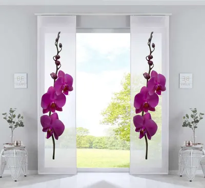 Two white panel curtains with purple orchid prints are displayed in a room with a large window showing a green outdoor scene.