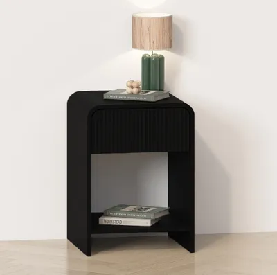 A black nightstand with a drawer and an open shelf, placed against a white wall.