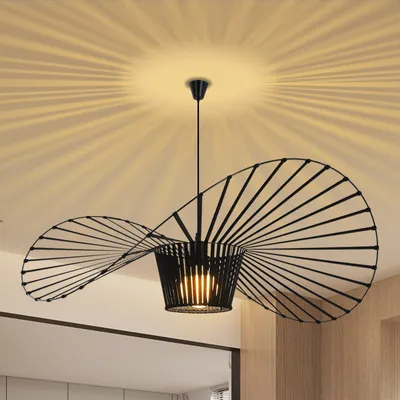 A black, modern pendant light with a wide, spiraling shade is shown hanging from a ceiling. The light casts a starburst pattern on the ceiling.