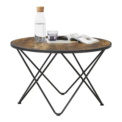 A round coffee table with a wood-look top and black metal legs, set against a white background. A bottle of water and a glass are on the table.