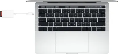 A top-down view of a laptop with a USB-C to SD card reader plugged into its side.