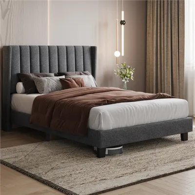 A bedroom scene featuring a dark gray upholstered bed frame with bedding.