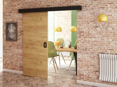 A sliding door in a brick wall interior, leading to a dining area with chairs and a table.