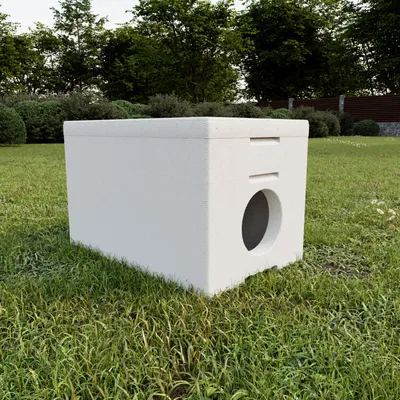 A white insulated cat house with a circular entrance sits on a grassy lawn.
