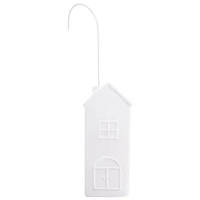 A white house-shaped radiator humidifier hangs from a hook against a white background.