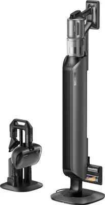 A cordless stick vacuum cleaner and its accessories are displayed against a white background. The vacuum is shown in its charging and self-emptying station, and a smaller handheld unit with attachments is also present.