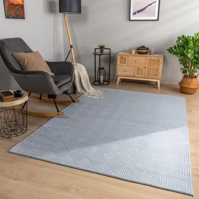 A cozy living room scene with a rocking chair, a rug, and a wooden cabinet.