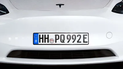 Close-up of the front of a white Tesla car, showing the license plate.