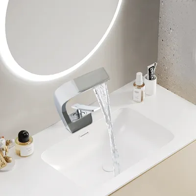 A modern bathroom sink with a waterfall faucet running.