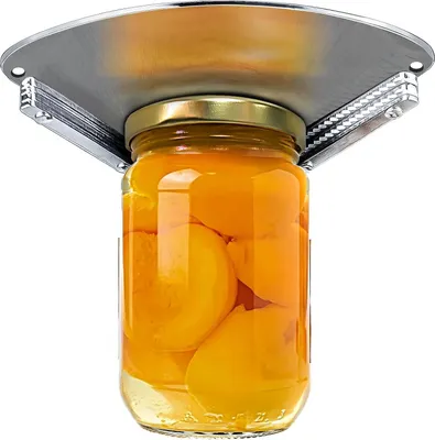 A jar of canned peaches is being held by a silver jar opener attached to a surface above.