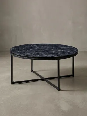 Design-Couchtisch in 3/4-Ansicht, die runde schwarze Marmor-Optik Platte und das gekreuzte Stahlgestell betonend, ideal für das moderne Wohnzimmer._#sku_BARWL6.247#
