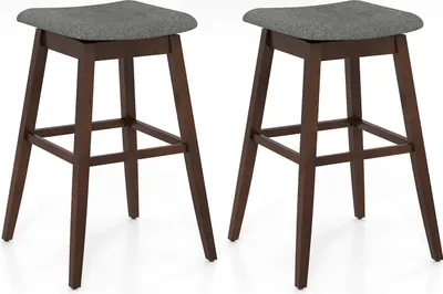 Two brown wooden bar stools with gray upholstered seats are shown against a white background.