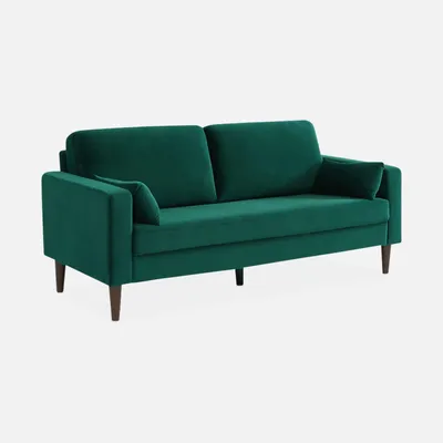 A green velvet sofa with wooden legs is shown against a white background.