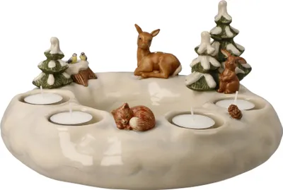 A ceramic advent wreath with winter-themed figurines and tea light holders.