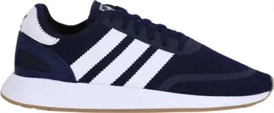 A side view of a navy blue Adidas sneaker with white stripes.