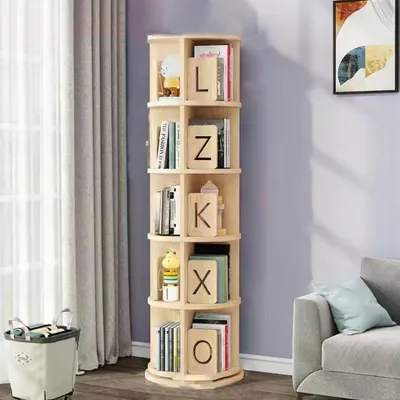 A rotating wooden bookshelf filled with books and decorative items, placed in a room next to a window and a sofa.