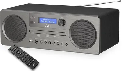 A JVC mini-tower stereo system with a remote control in front of it, set against a white background.
