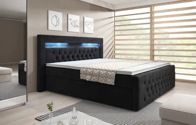 A bedroom scene featuring a black upholstered box spring bed with LED lighting.