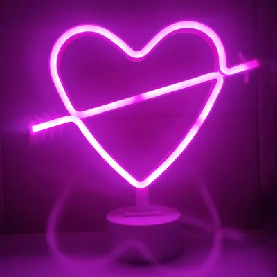 A pink neon heart with an arrow through it, standing on a white base.