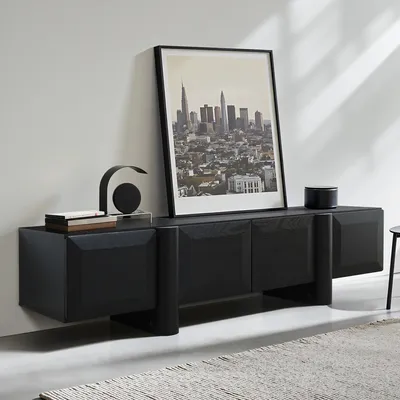 A modern black wooden TV cabinet with a framed cityscape artwork above it, placed against a white wall.