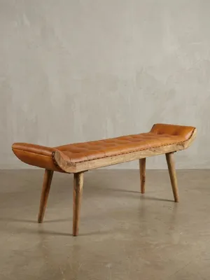Schräge 3/4-Ansicht der 125 cm langen Polsterbank. Die geschwungene Form und die robusten Beine aus Mangoholz unterstreichen das Vintage-Modern-Design für den Flur._#sku_BARWL6.479#